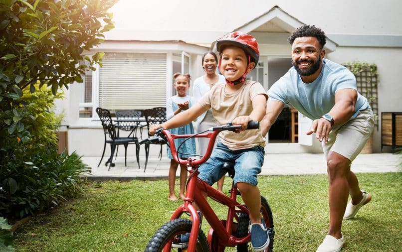 un enfant qui apprend à faire du vélo avec sa famille